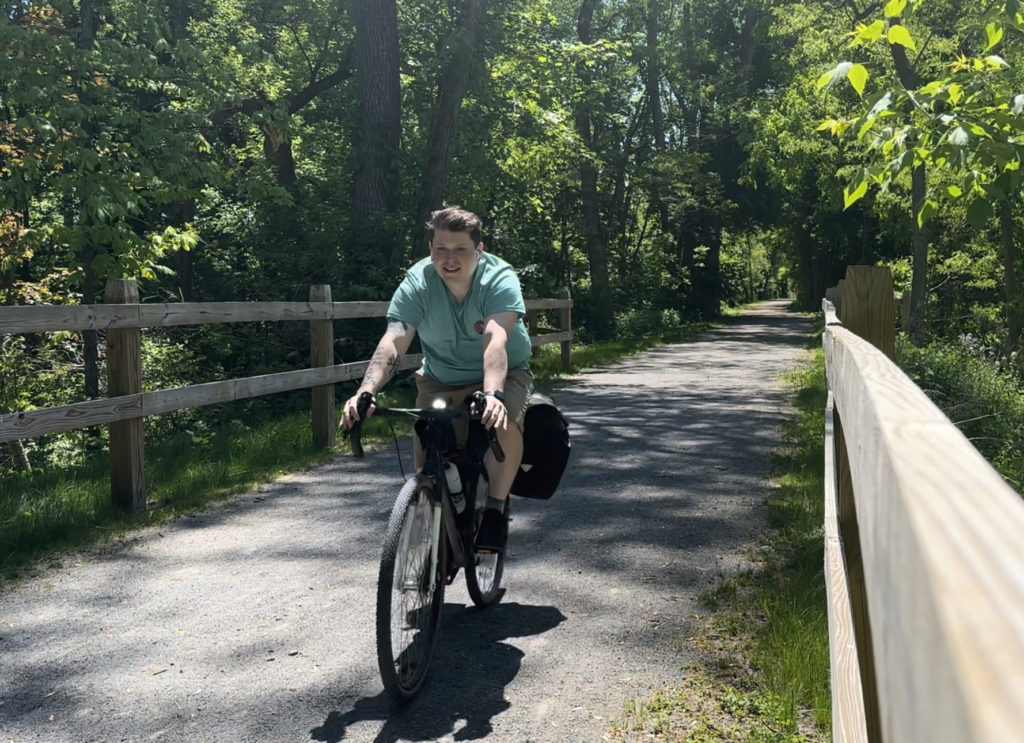 Man riding a bike on a bicycle trail on his way to bike camp.